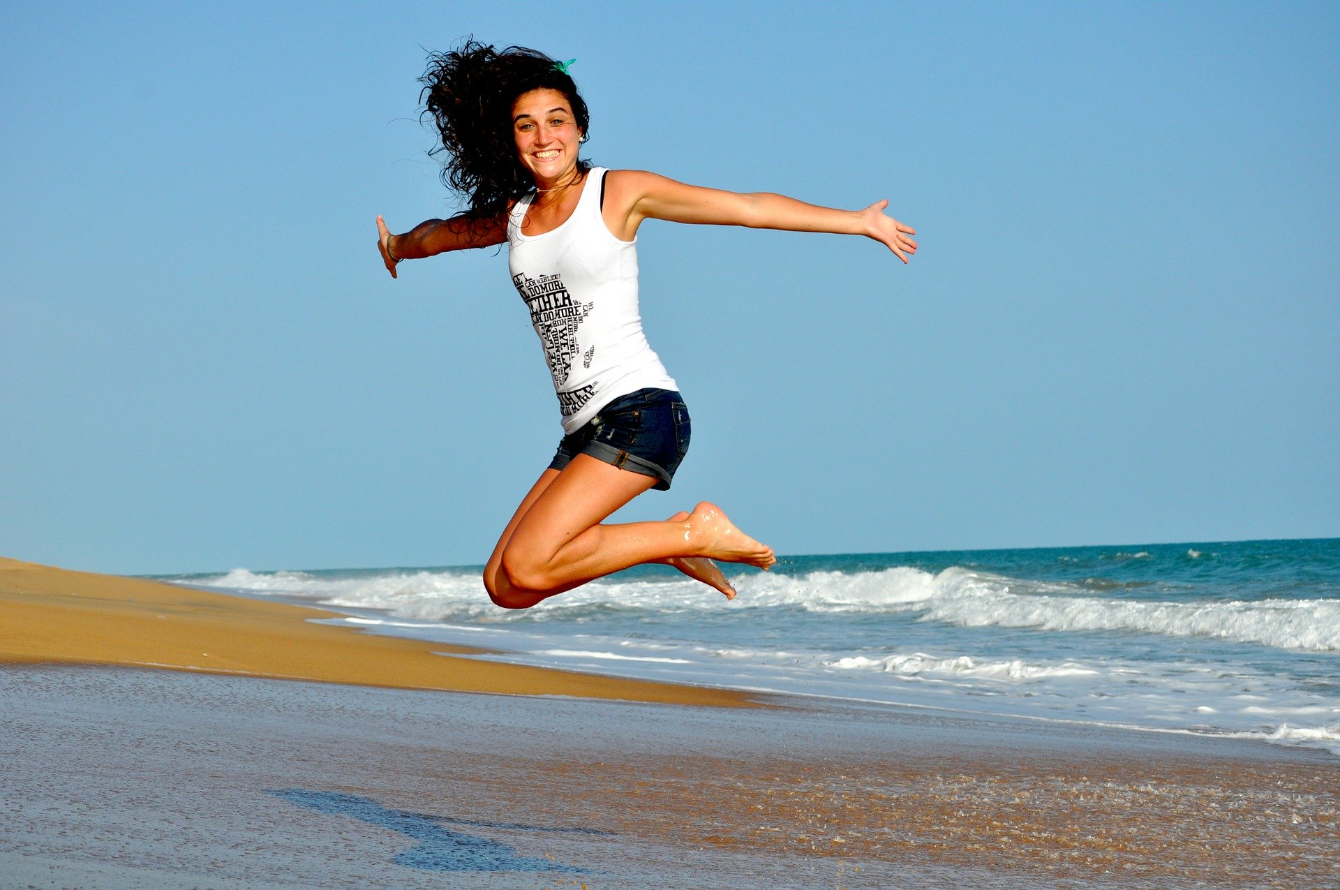 Happy girl jumps on the beach